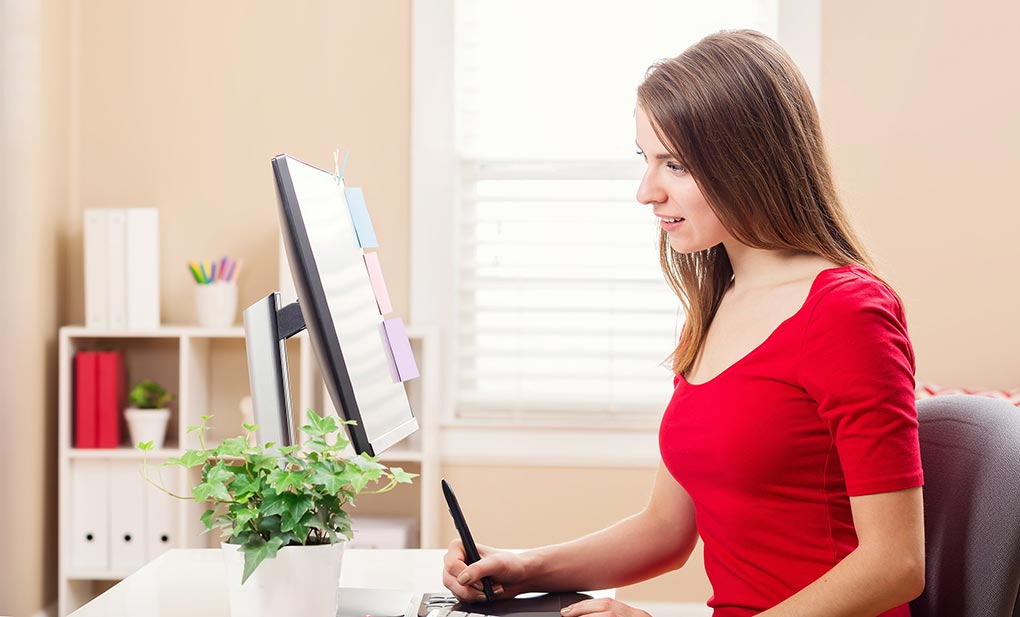 Woman working with a pen stylus tablet in her home office