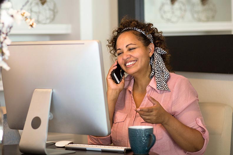 Woman talking on the phone in front of a computer